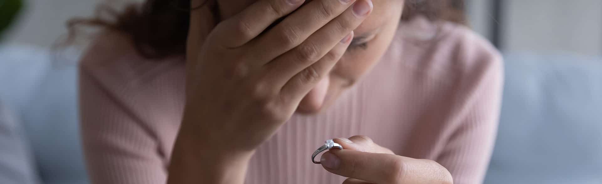 Engagement ring held by distraught woman